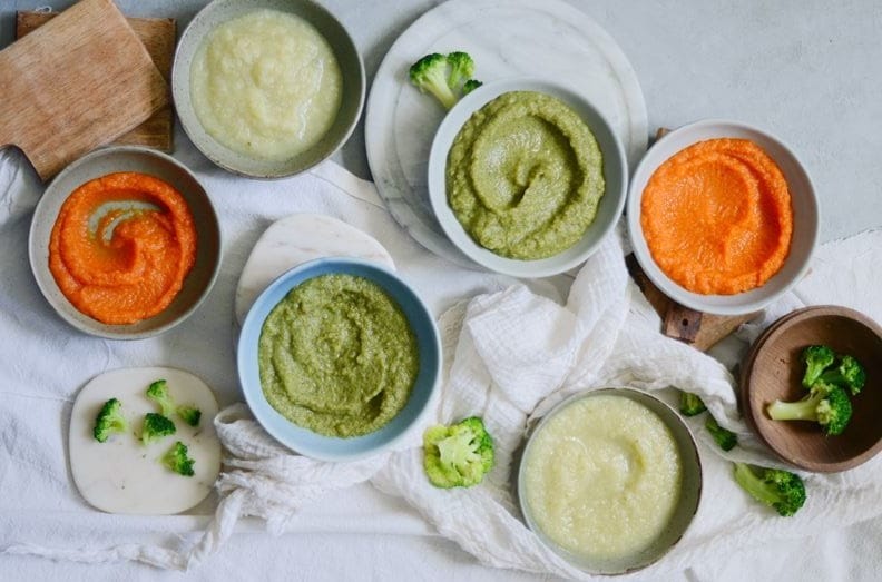 Assortiment de purées maison pour bébé (carotte, brocoli, courgette), présentées dans de petits bols, illustrant la diversification alimentaire et les premiers repas faits maison.