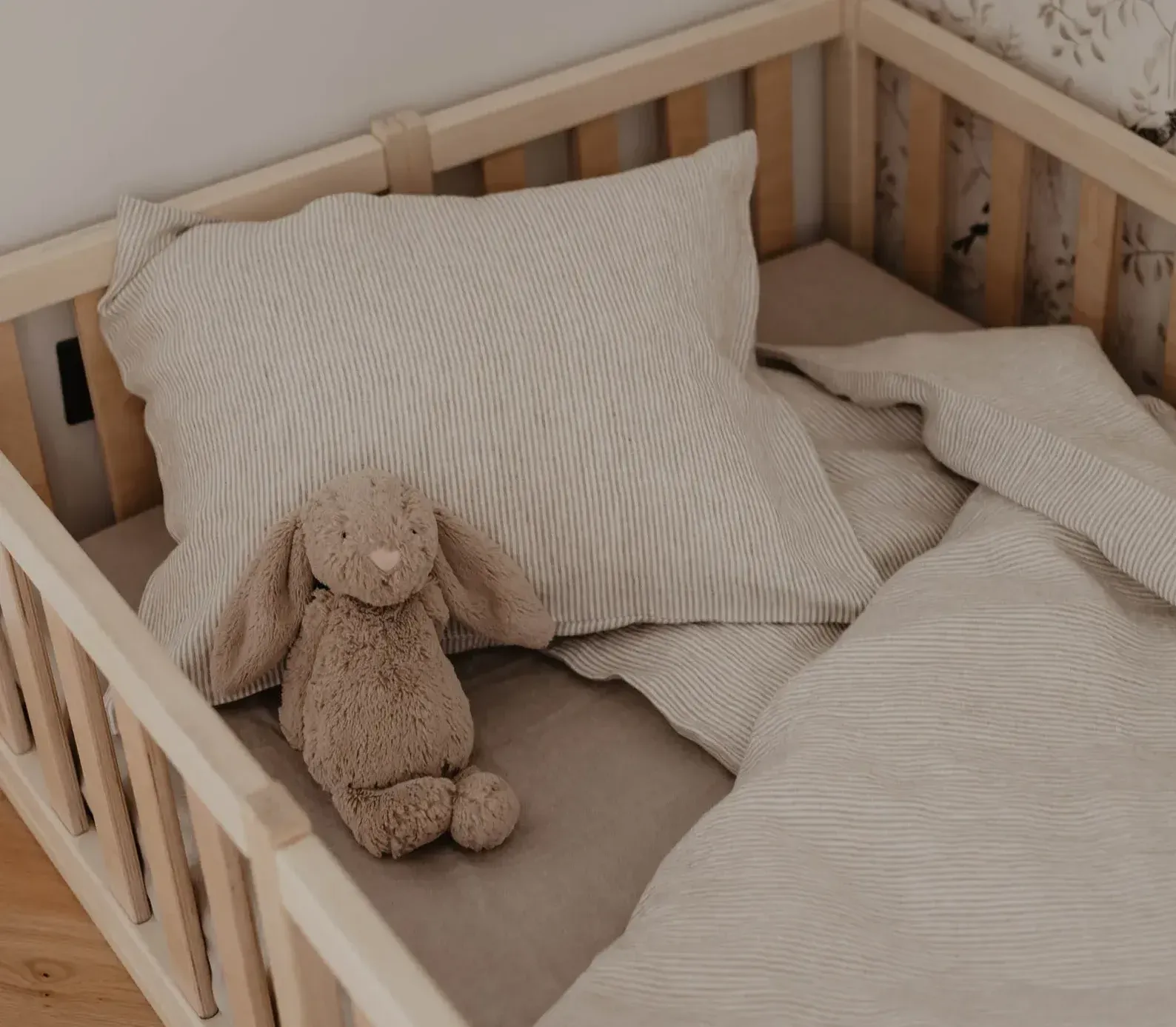 Lit de bébé dans une chambre douce et apaisante, avec matelas, linge de lit et peluche, illustrant un environnement sécurisé et propice au sommeil du bébé.