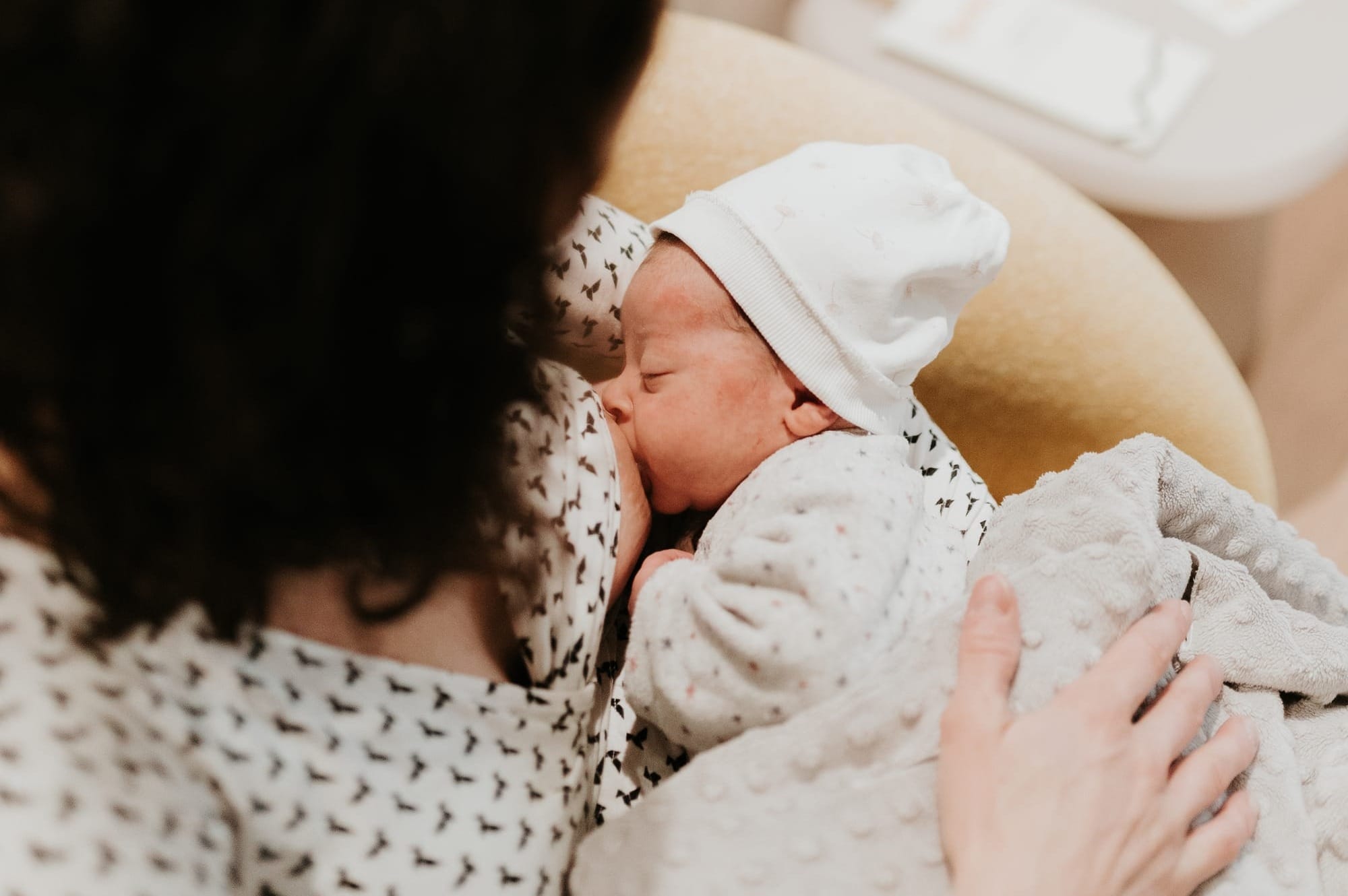 Maman allaitant son nouveau-né confortablement installé dans ses bras, moment de peau à peau favorisant le lien et un allaitement serein.