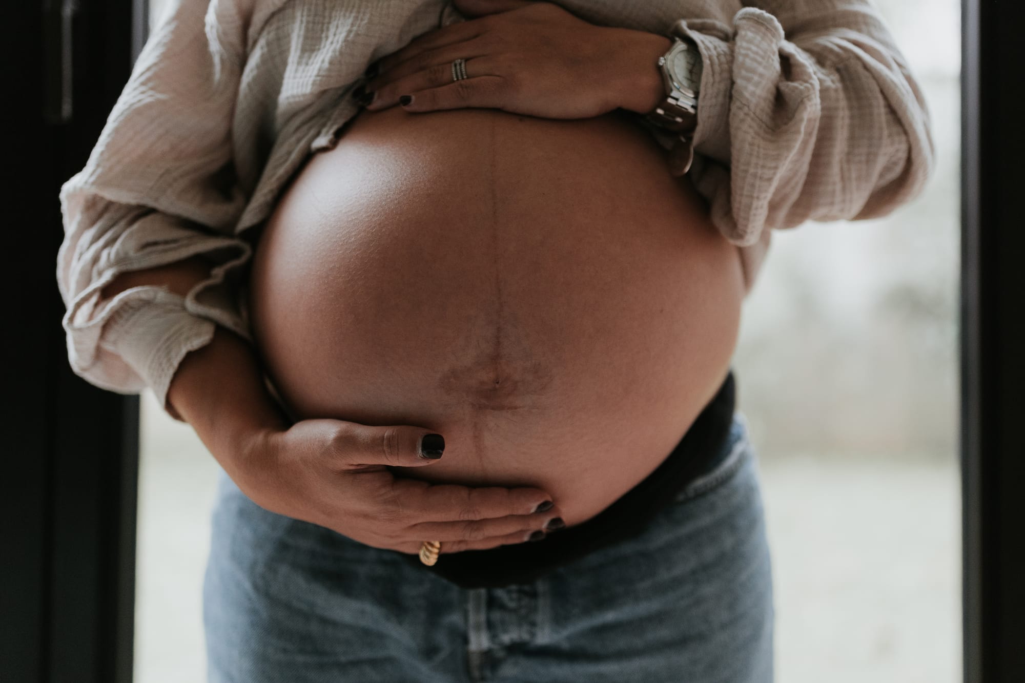 Ventre de femme enceinte tenu par ses mains, symbole de grossesse et de maternité, illustrant la période prénatale et l’accompagnement des futures mamans.