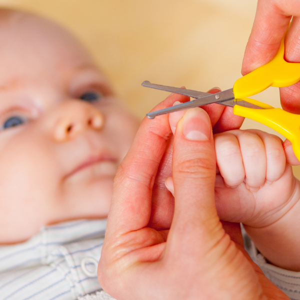 Main d'un bébé pendant une coupe d'ongles, avec un ciseau à bouts ronds utilisé par un parent pour une coupe sécurisée