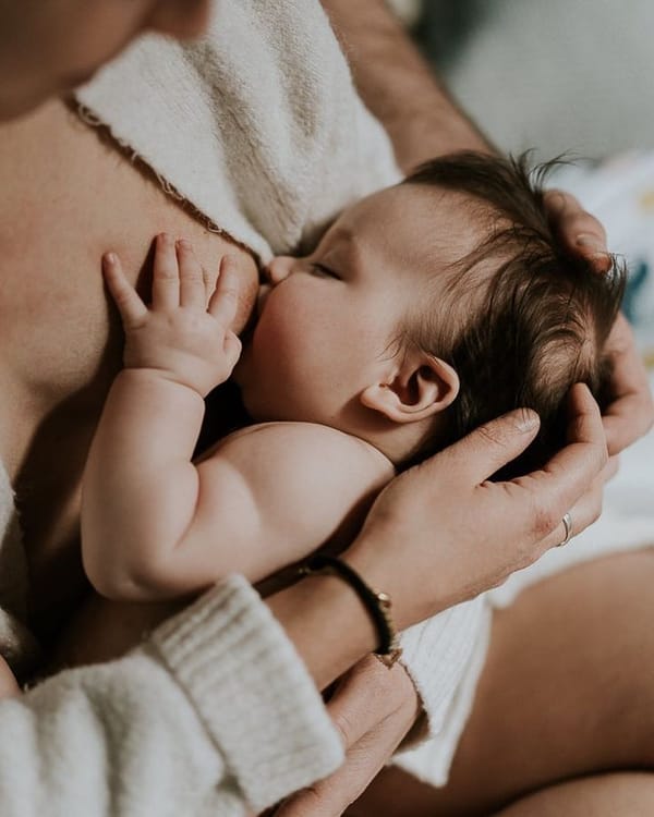Bébé allaité tendrement dans les bras de sa maman, en contact peau à peau, moment doux et apaisant d’allaitement.